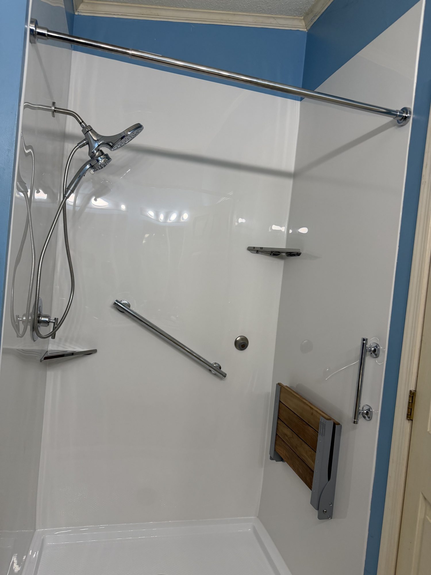 A real Carolina Bath Solutions walk-in shower with grab bars and a fold-down seat